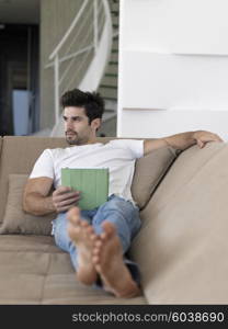 Handsome relaxed young businessman working from home on tablet computer