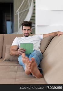 Handsome relaxed young businessman working from home on tablet computer