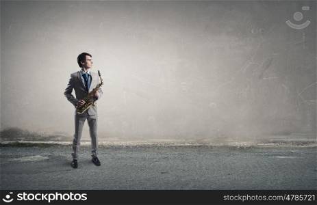Handsome saxophonist. Young man in suit with saxophone in hands