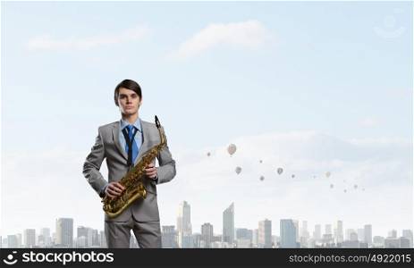 Handsome saxophonist. Young man in suit with saxophone in hands
