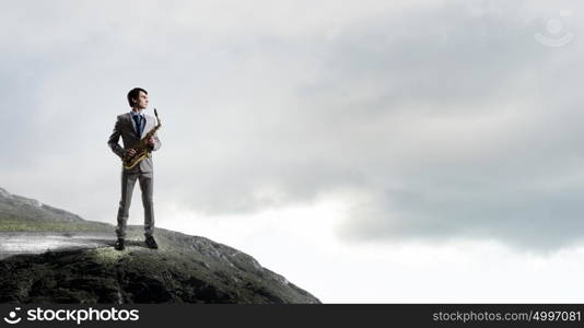 Handsome saxophonist. Young man in suit with saxophone in hands