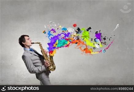 Handsome saxophonist. Young man playing saxophone and paint splashes coming out