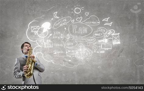 Handsome saxophonist. Young man playing saxophone and sketches at bacground