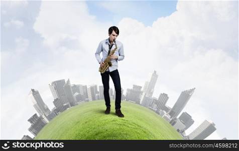 Handsome saxophonist. Young man playing saxophone on green city scene