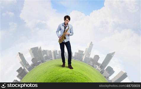 Handsome saxophonist. Young man playing saxophone on green city scene