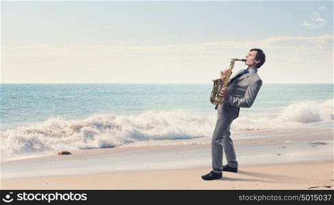 Handsome saxophonist. Young man playing saxophone on sea coast