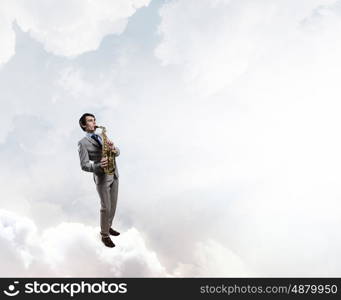 Handsome saxophonist. Young man standing on cloud playing saxophone