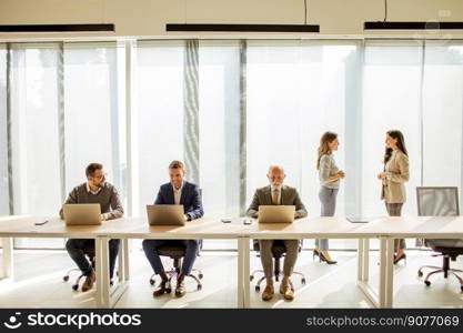 Handsome senior businessman working together with young business people in the office