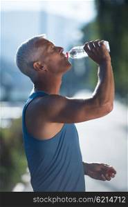 handsome senior jogging man drinking fresh water from bottle after mornig run