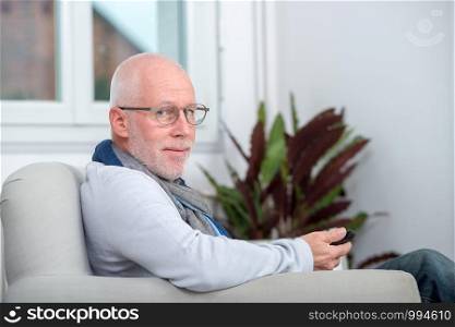 handsome senior man using a phone on the sofa