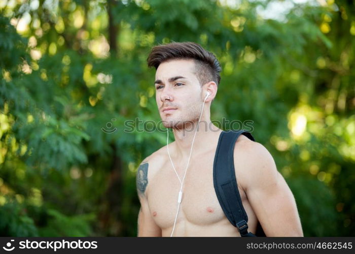 Handsome shirtless young man doing hiking while listening to music