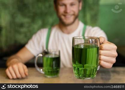 handsome smiley man celebrating st patrick s day with drinks