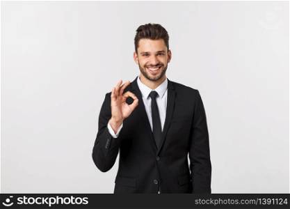 Handsome smiling businessman showing ok sign with fingers over gray background. Handsome smiling businessman showing ok sign with fingers over gray background.