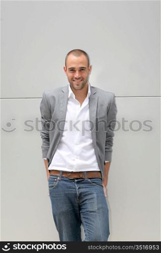 Handsome smiling man leaning on wall