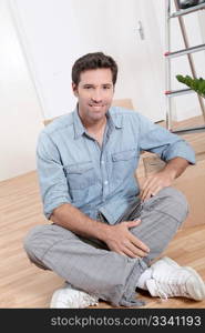 Handsome smiling man sitting on the floor