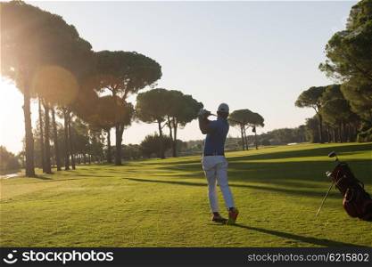 handsome sporty man, golf player hitting shot with club on course at beautiful morning