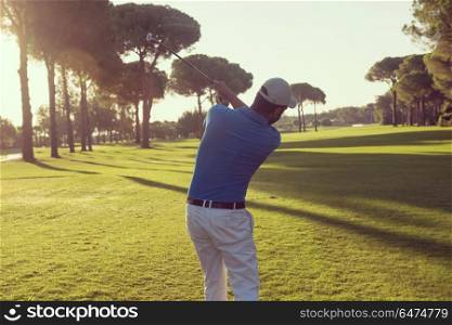 handsome sporty man, golf player hitting shot with club on course at beautiful morning. golf player
