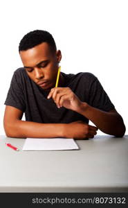 Handsome student thinking concentrating focussing for test examination sitting at desk, on white.