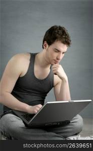 handsome student young man sit working on laptop over gray background