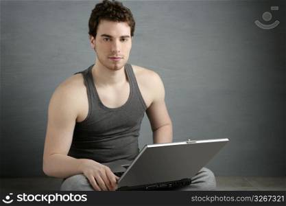 handsome student young man sit working on laptop over gray background