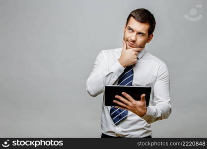 Handsome stylish caucasian businessman on grey background with copy space. Handsome stylish businessman on grey background