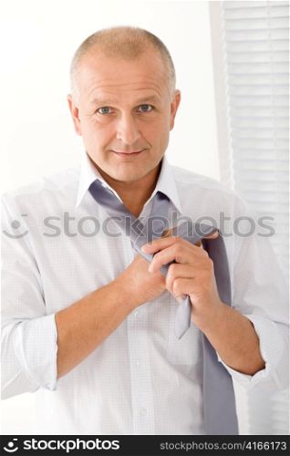 Handsome stylish mature business man tie a tie white shirt