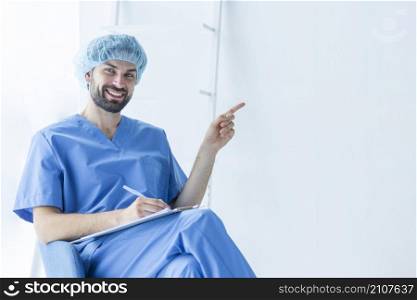 handsome surgeon with clipboard pointing empty space
