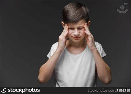 Handsome teenager boy wearing casual white t-shirt standing over isolated background suffering from headache desperate and stressed because pain and migraine. Hands on head. Handsome teenager boy wearing casual white t-shirt standing over isolated background suffering from headache desperate and stressed because pain and migraine. Hands on head.