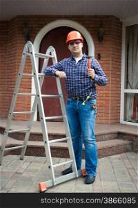 Handsome worker posing with tools against house entrance