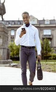 Handsome young African American businessman using a mobile phone on a street
