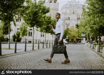 Handsome young African American businessman using a mobile phone on a street