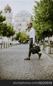 Handsome young African American businessman using a mobile phone while crossing a street