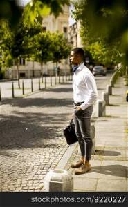 Handsome young African American businessman waitng a taxi on a street