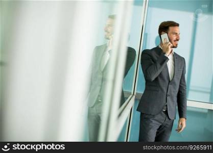 Handsome young bisinessman with mobile phone in front of office building
