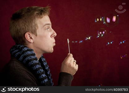 Handsome young blonde man blowing a bubbles