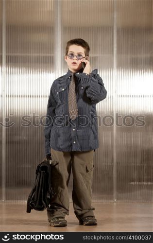 Handsome young boy in adult business clothes on phone