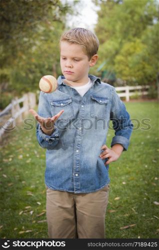 Handsome Young Boy Tossing Up His Baseball in the Park.