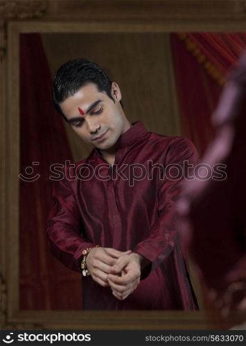 Handsome young bridegroom&rsquo;s reflection in mirror while getting dressed