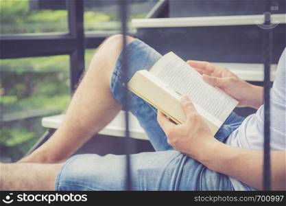 Handsome young business asian man in casual clothes reading book with leisure in living room, education for study knowledge concept.