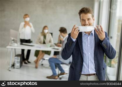 Handsome young business man putting his protective facial mask in the office space