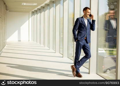 Handsome young business man using mobile phone in the modern office hallway