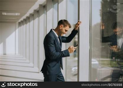 Handsome young business man using mobile phone in the modern office hallway