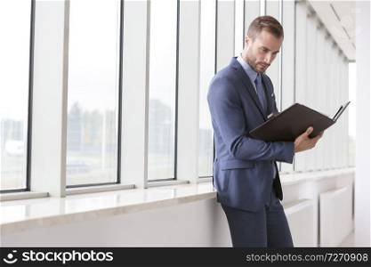 Handsome young businessman reading file in new office