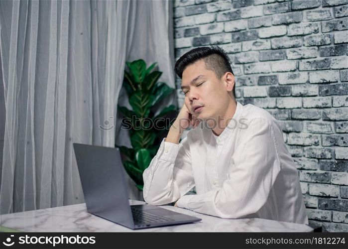 Handsome young businessman sleep at home with laptop on desk