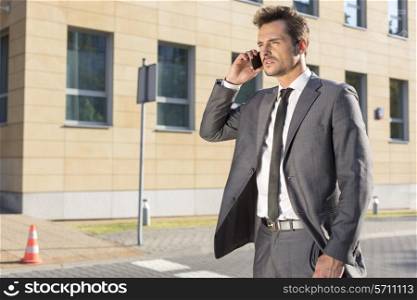 Handsome young businessman using cell phone outdoors