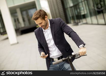 Handsome young businessman using mobile phone on electric scooter