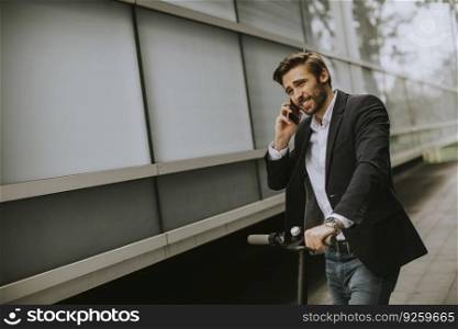 Handsome young businessman using mobile phone  on electric scooter