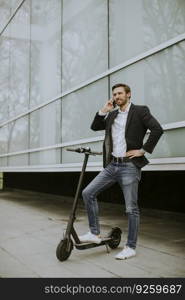 Handsome young businessman using mobile phone  on electric scooter