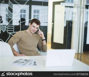 Handsome young businessman using smart phone in office
