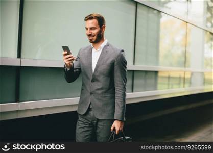 Handsome young businessman with mobile phone by the office building